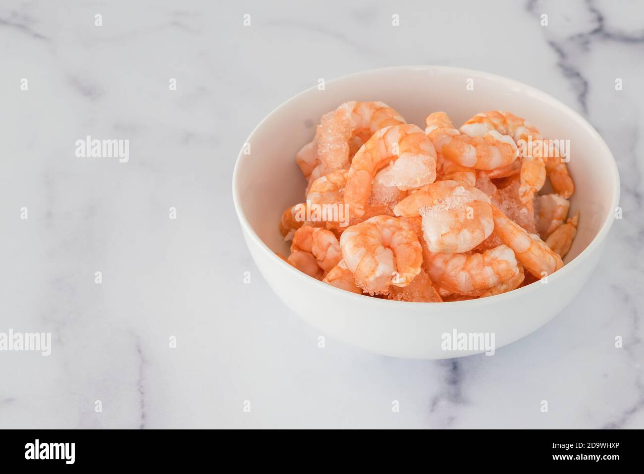 Frozen shrimp close up in a bowl on marble background Stock Photo