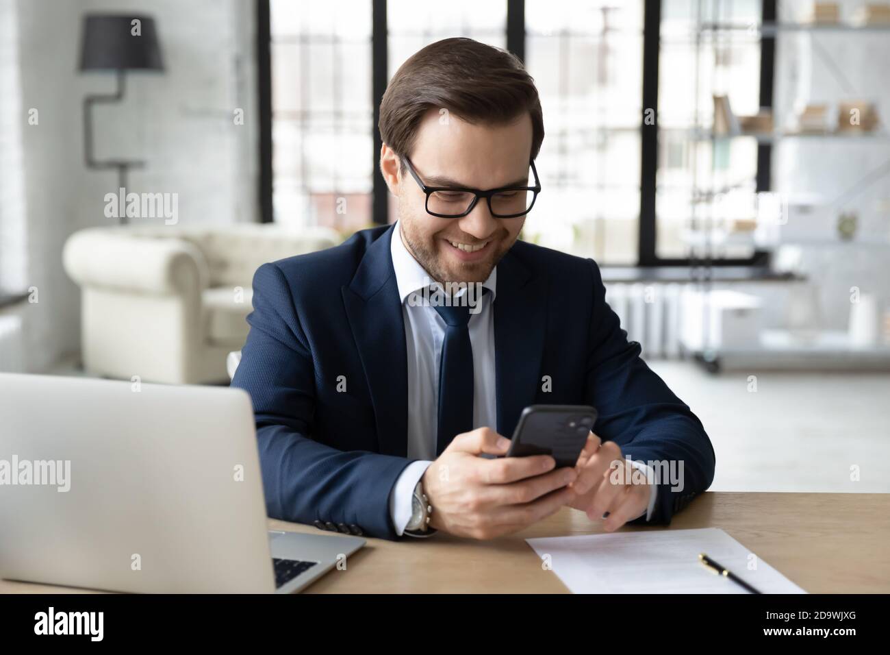 Smiling young male ceo executive manager using smartphone. Stock Photo