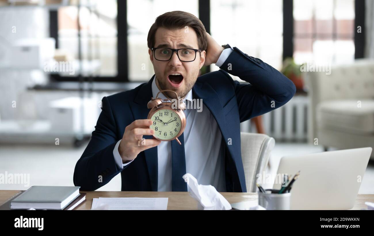 Stressed young businessman holding clock in hands. Stock Photo