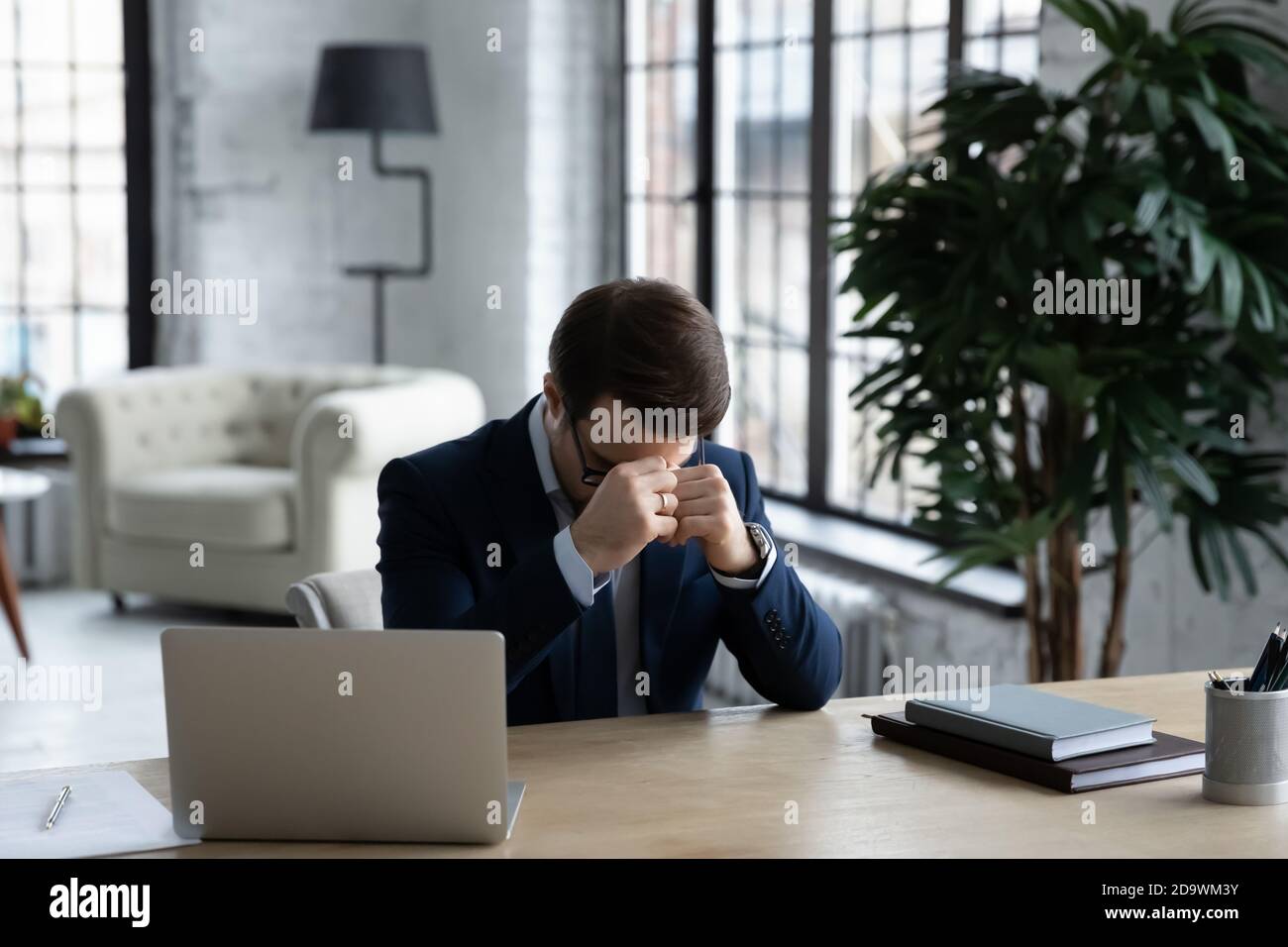 Stressed young ceo manager sitting at table with head down. Stock Photo