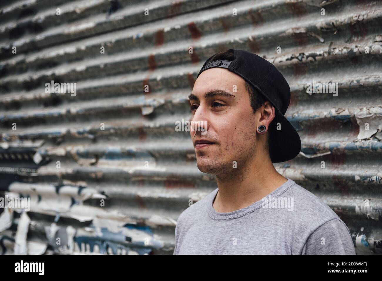 Closeup shot of a cool young man posing in front of an old garage wall Stock Photo