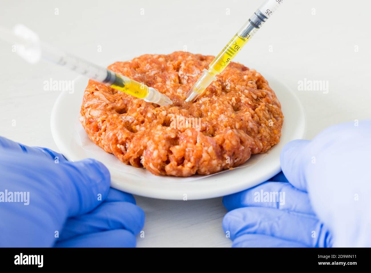 raw beef burger full of antibiotics. Syringes stuck in meat, Concept, Unhealthy food Stock Photo