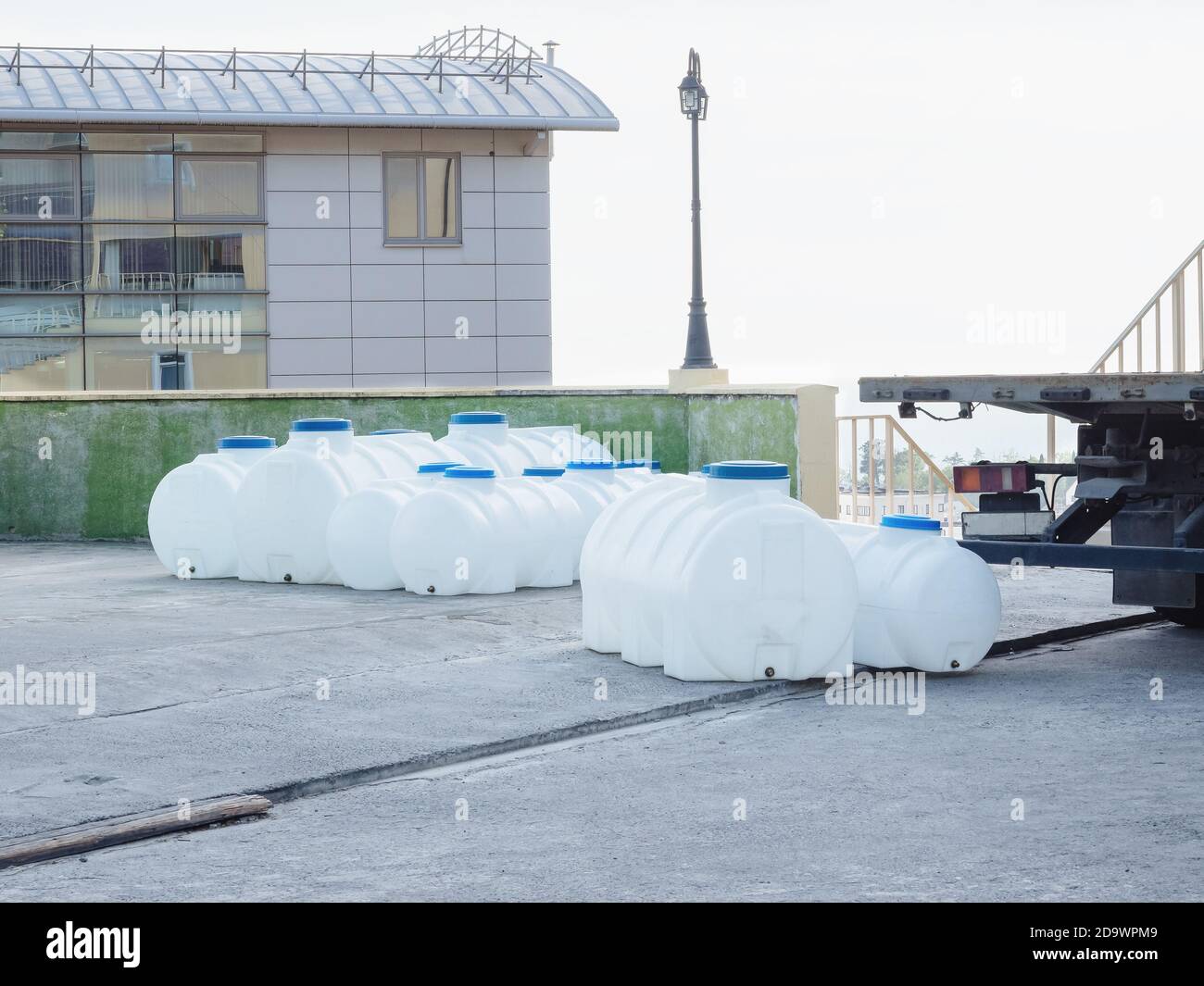 Large plastic containers of water with blue lids stand outside Stock Photo Alamy
