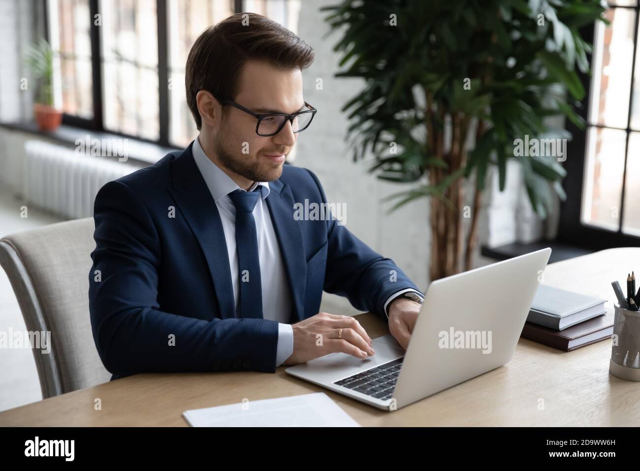 Smiling young businessman working on project online. Stock Photo