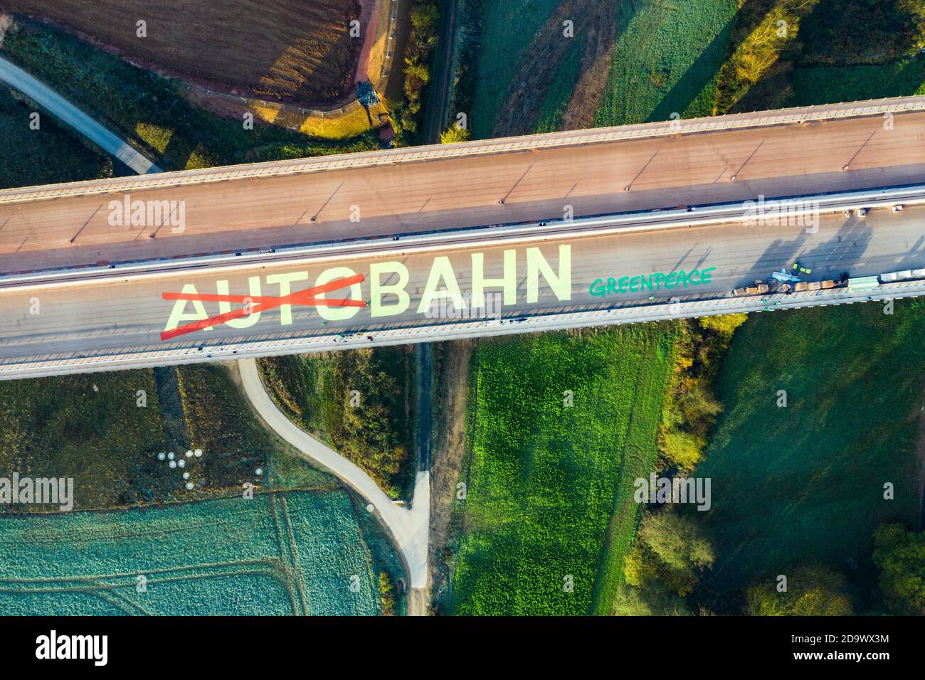 Schwalmstadt, Germany. 08th Nov, 2020. The lettering 'Autobahn', where the first part of the word 'Auto' is crossed out, was applied by Greenpeace in eight-metre letters on a section of the A49 road that has not yet been cleared. Greenpeace activists are thus demonstrating on a valley bridge against the expansion of the controversial A49 in Hesse. (drone picture) Credit: Andreas Arnold/dpa/Alamy Live News Stock Photo