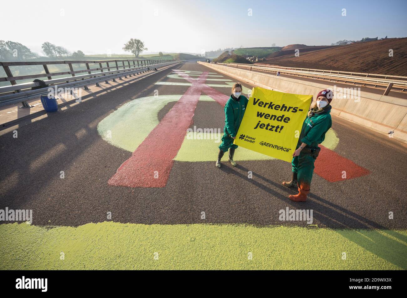 Schwalmstadt, Germany. 08th Nov, 2020. Two activists hold a poster 'Verkehrswende jetzt!' in front of the protest sign on the road. Greenpeace activists demonstrate on a viaduct of the controversial A49 in Hesse. With letters eight metres in size, a 90-metre-long lettering 'AUTOBAHN' with the first part of the word 'Auto' crossed out, is written in chalk paint on a construction section that has not yet been cleared. Credit: Andreas Arnold/dpa/Alamy Live News Stock Photo