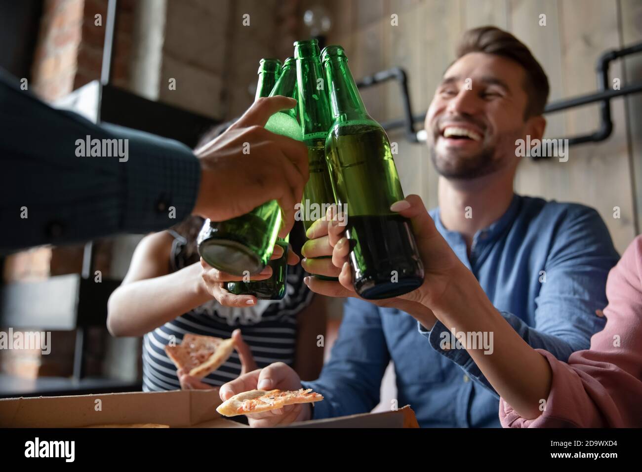 Diverse millennial friends making toast for meeting raising beer bottles Stock Photo