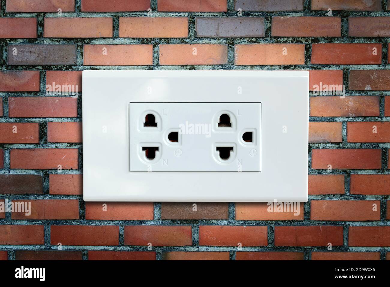 AC power plug on the vintage brick wall. Stock Photo