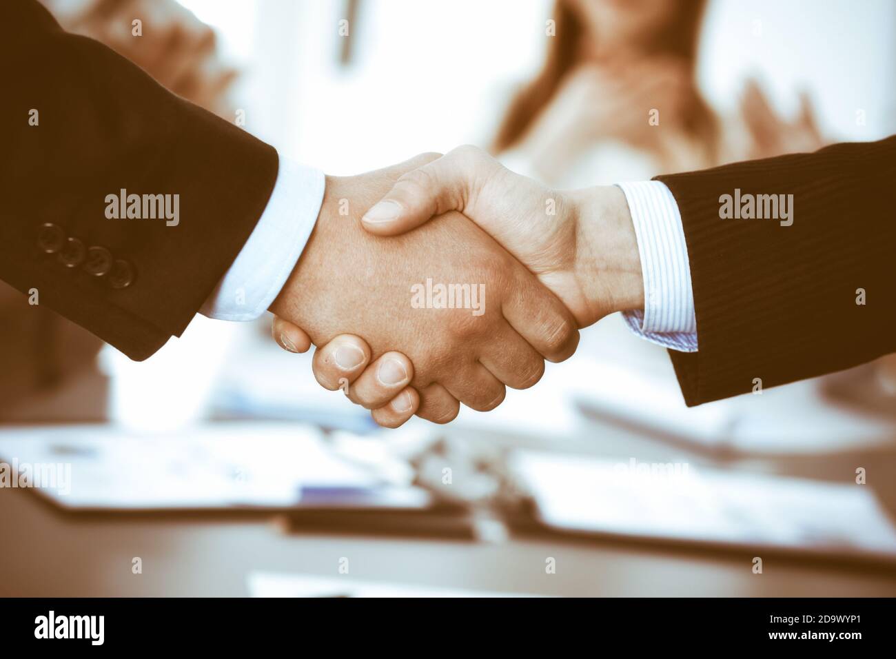 Business people shaking hands at meeting while theirs colleagues ...