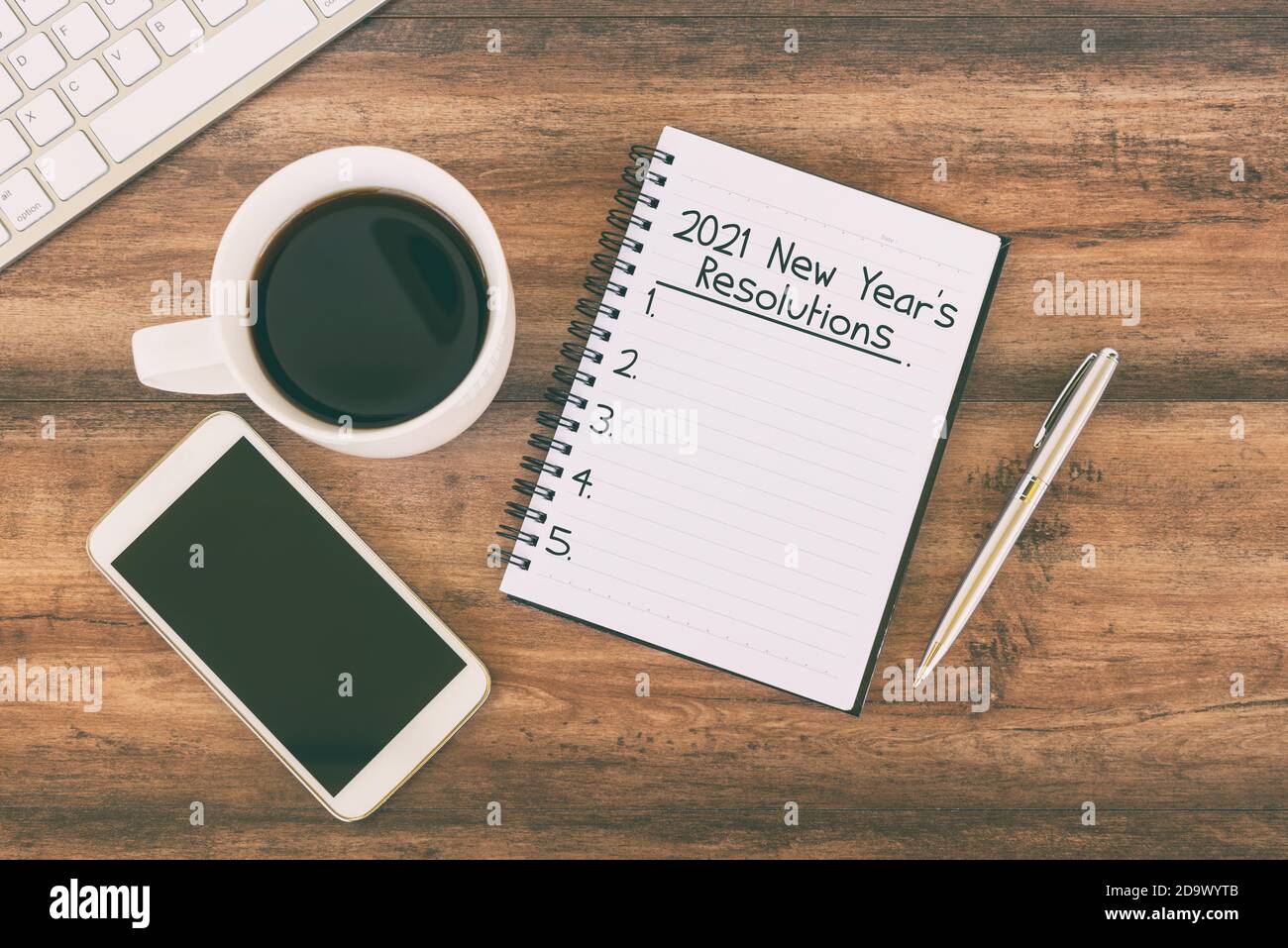 2021 New Year resolution text on notepad with cup of coffee, smart phone, pen Stock Photo