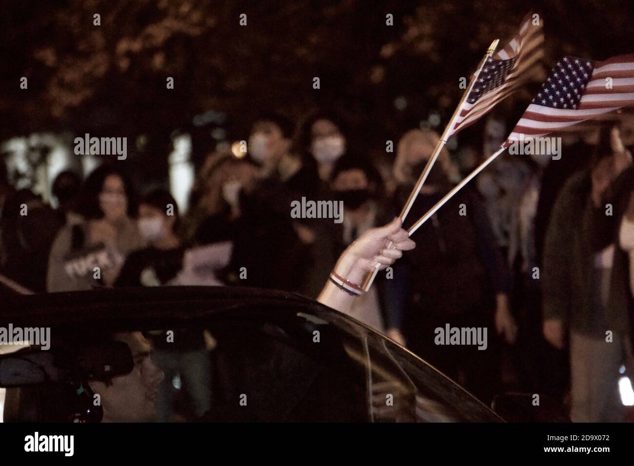 Oakland, California, USA. 7 Nov, 2020. Joe Biden/Kamala Harris supporters fill the streets to celebrate their victory over Donald Trump in the USA Presidential Election. Here they wave at a honking car caravan passing by Lake Merritt in Vice President-elect Kamala Harris' hometown. Credit: Kristin Cato/Alamy Live News Stock Photo