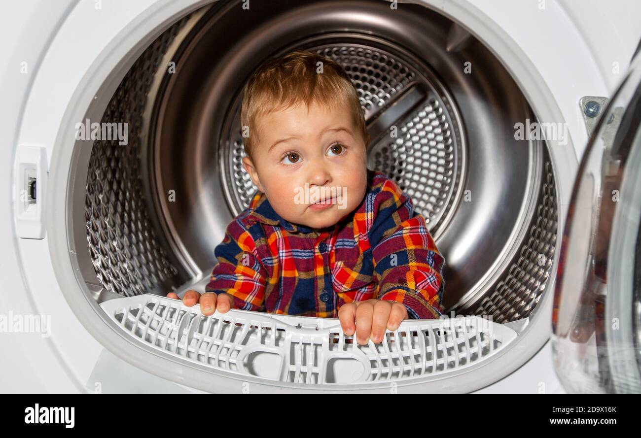 Close up of portrait lovely kid looks out from the washing machine