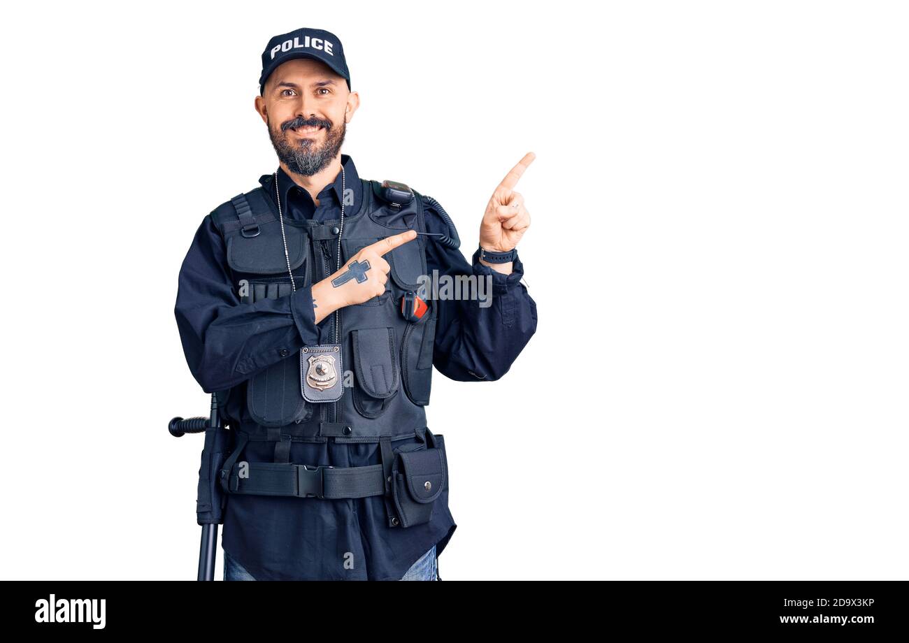 Young handsome man wearing police uniform smiling and looking at the camera pointing with two hands and fingers to the side. Stock Photo