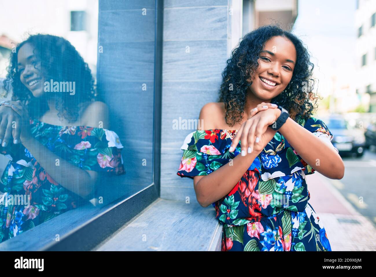 Young african american woman with curly hair smiling happy outdoors ...