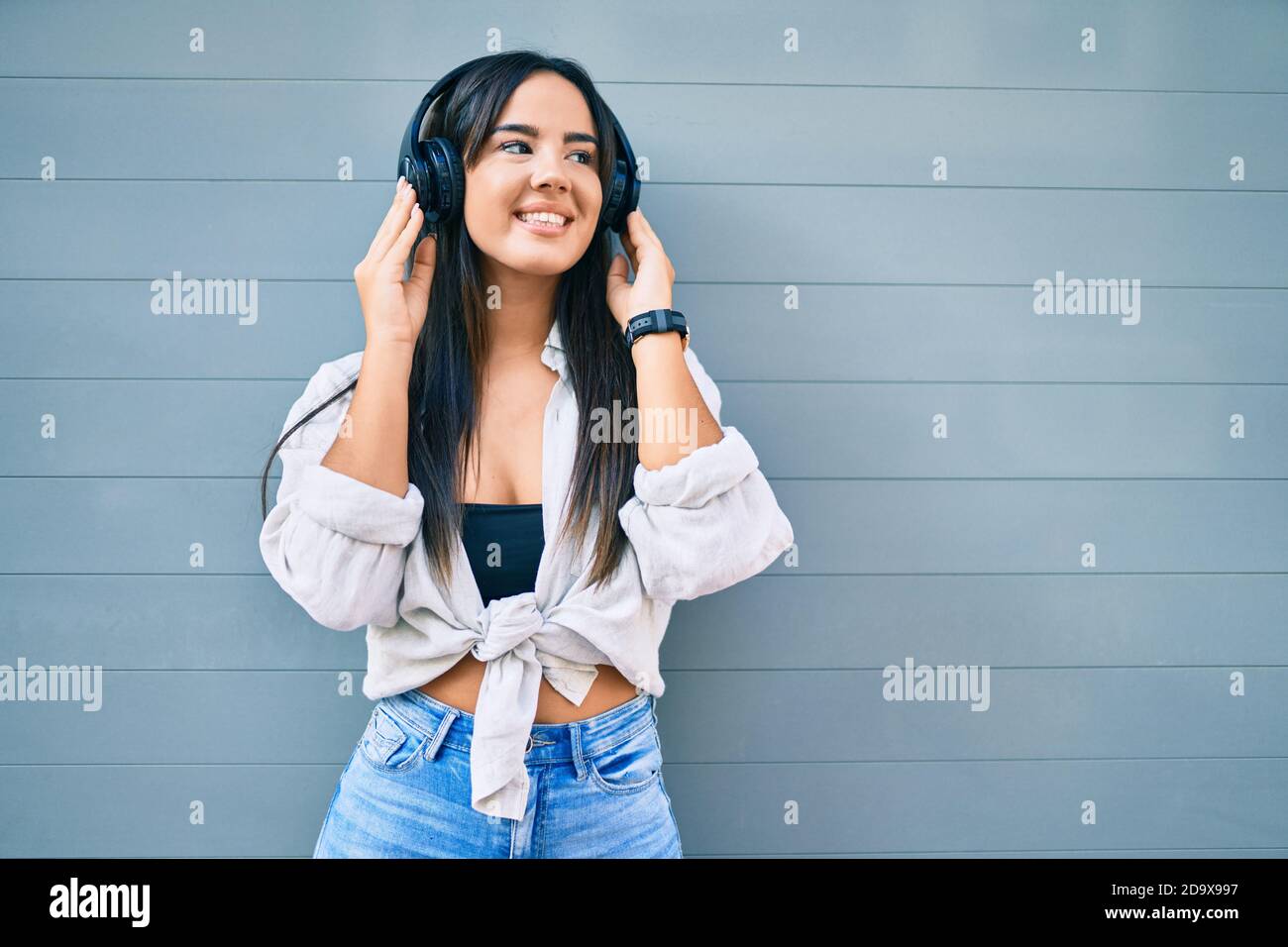 Young hispanic girl smiling happy listening to music using headphones ...