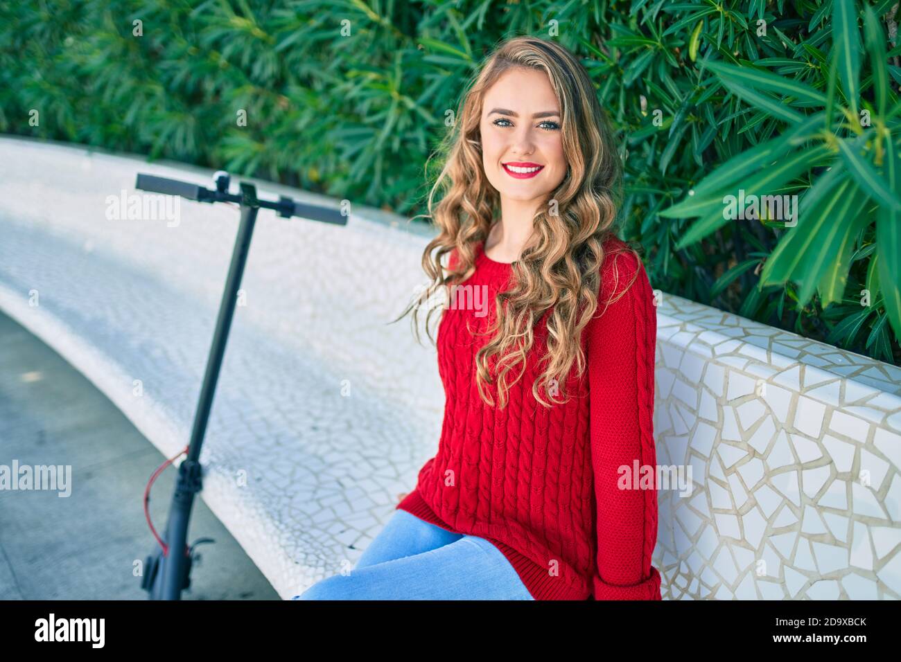 Young blonde girl smiling happy sitting on the bench at the park Stock ...