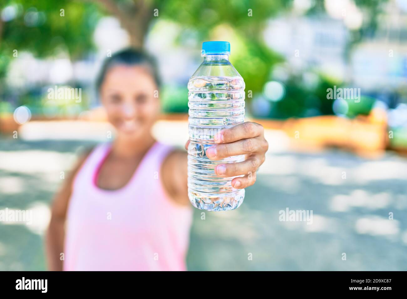 Middle age sportswoman smiling happy holding bottle of water at the ...