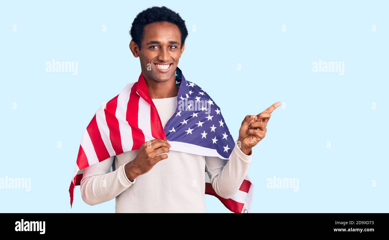African handsome man holding united states flag smiling happy pointing ...