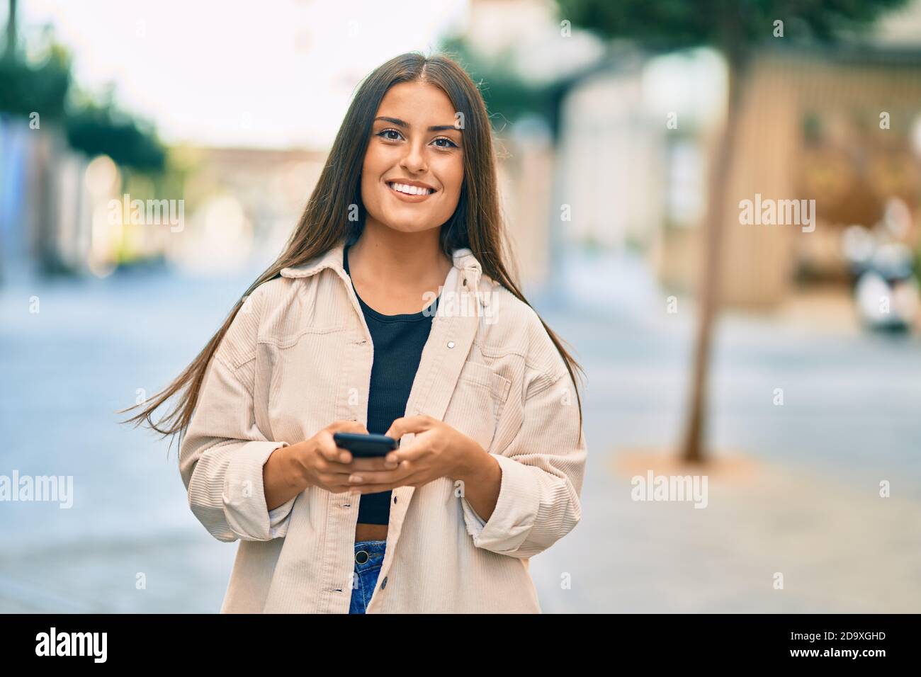 Young hispanic girl smiling happy using smartphone at the city Stock ...
