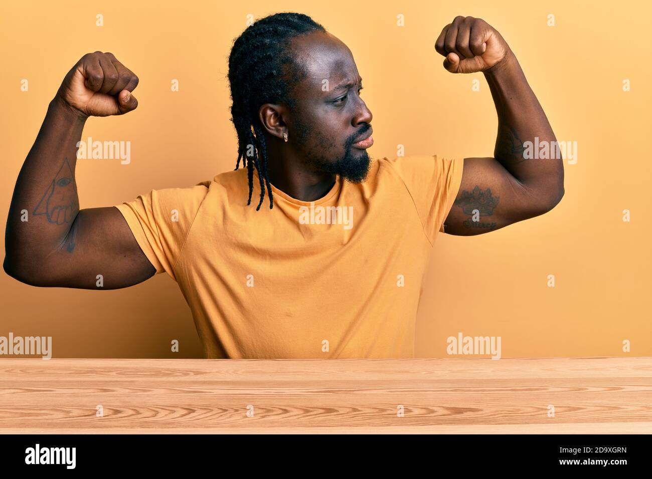 Handsome young black man wearing casual clothes sitting on the table ...
