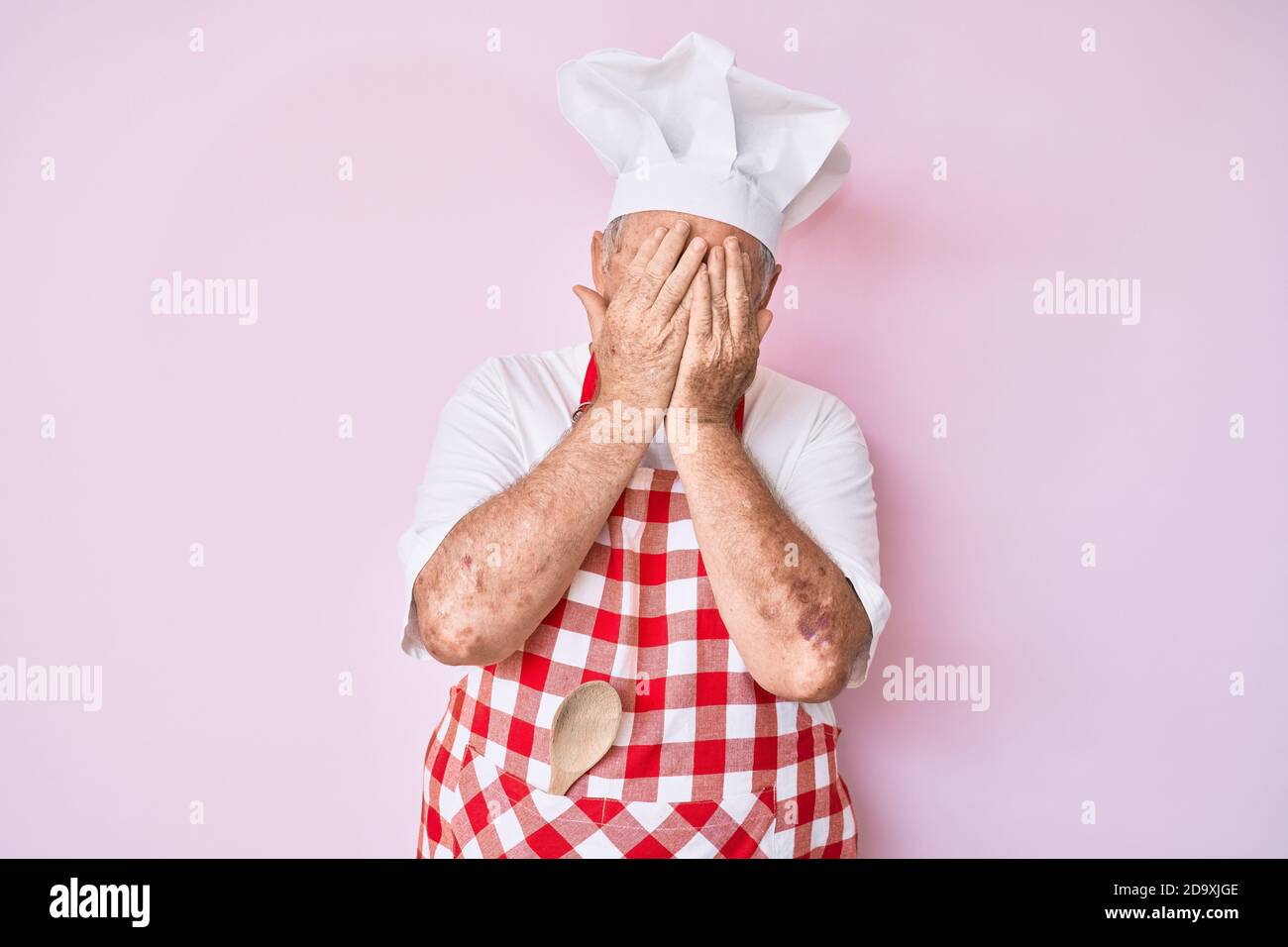 Senior grey-haired man wearing professional baker apron with sad ...