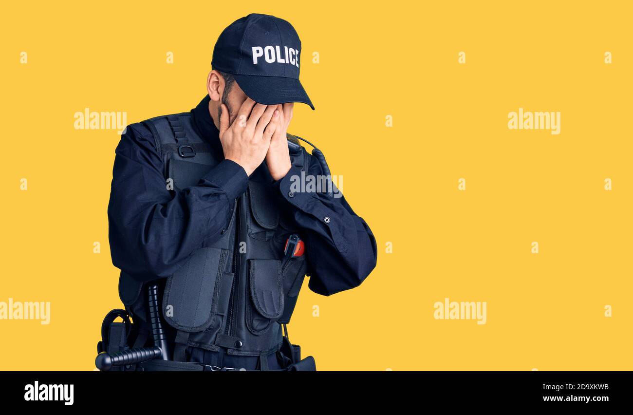 Young handsome man with beard wearing police uniform with sad expression covering face with hands while crying. depression concept. Stock Photo