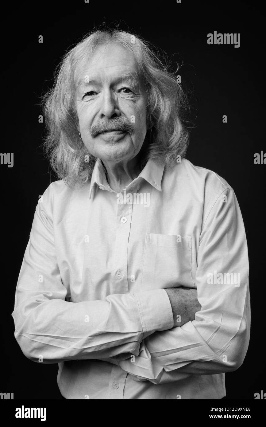 Senior businessman wearing pink shirt against gray background Stock Photo