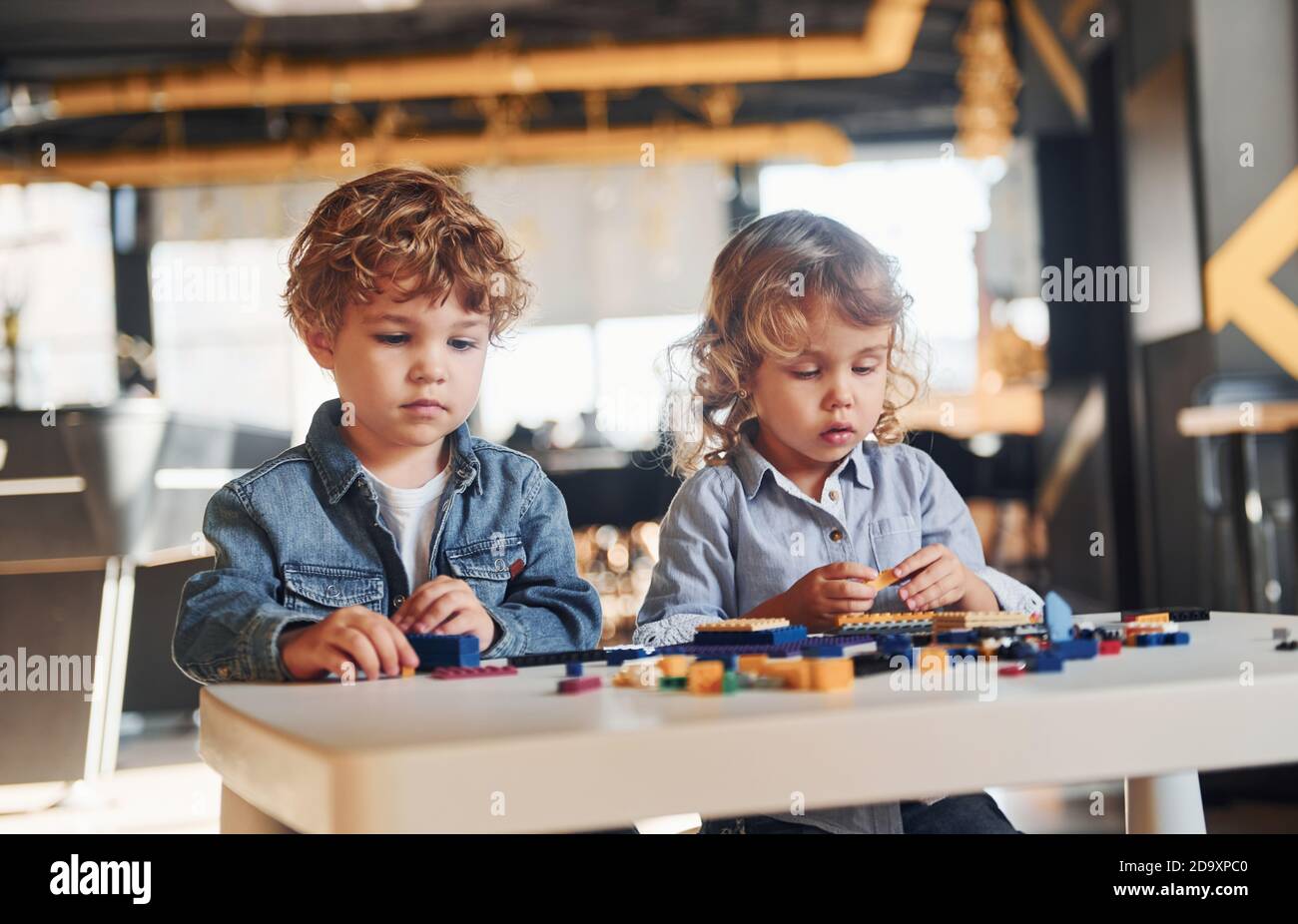 Little friends have fun with construction toys in playroom. Kindergarten educational games Stock Photo