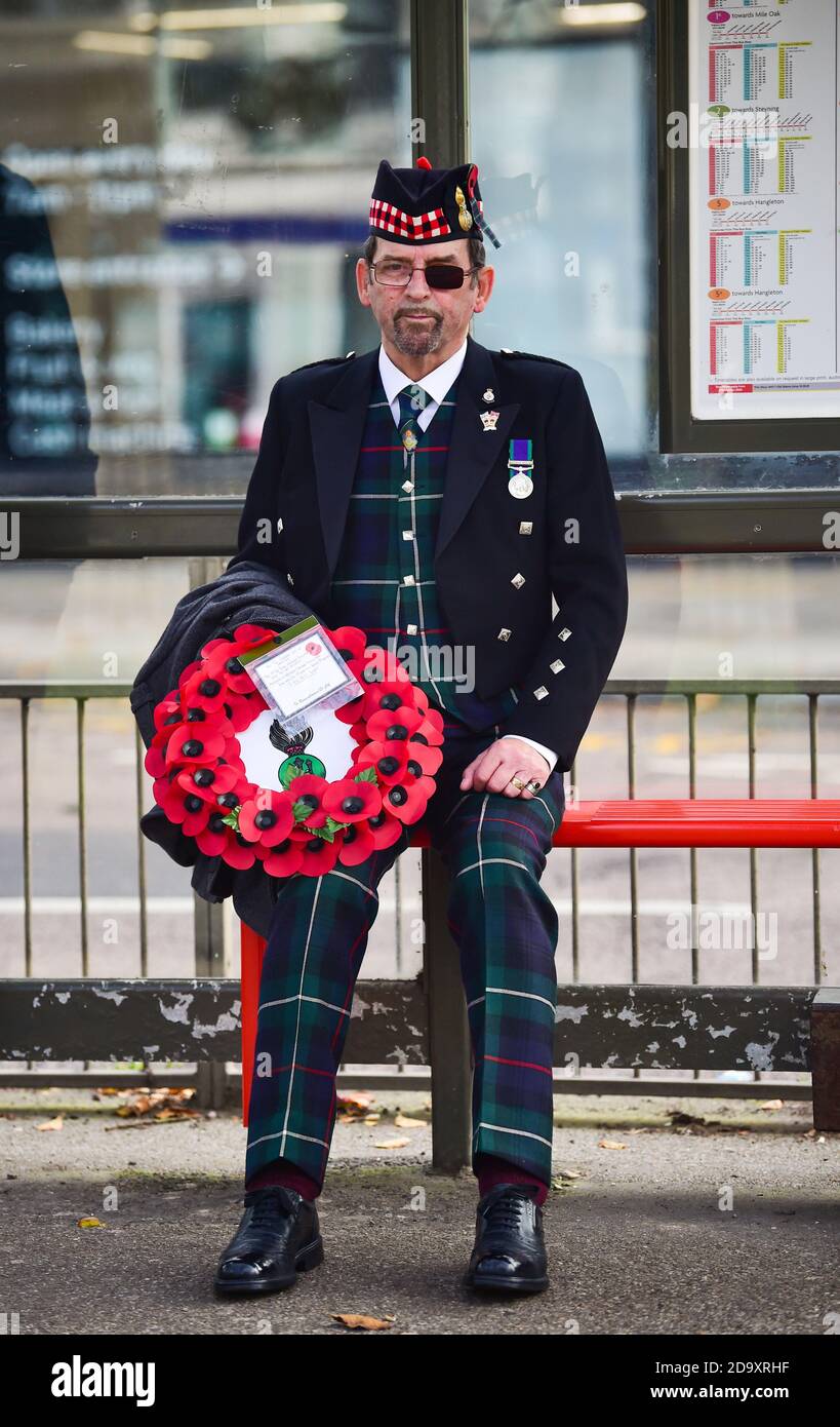 Brighton UK 8th November 2020 - Hugh Murray representing the 1st Battalion Royal Highland Fusiliers waits in a bus stop before taking part in the Act of Remembrance service held at the city's war memorial in the Old Steine today : Credit Simon Dack / Alamy Live News Stock Photo