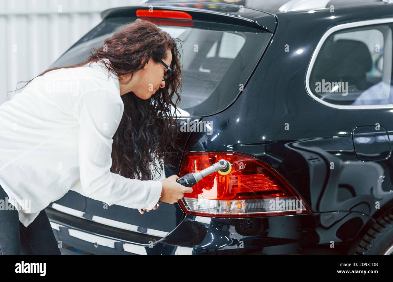 Woman with equipment cleaning modern automobile. Conception of service Stock Photo