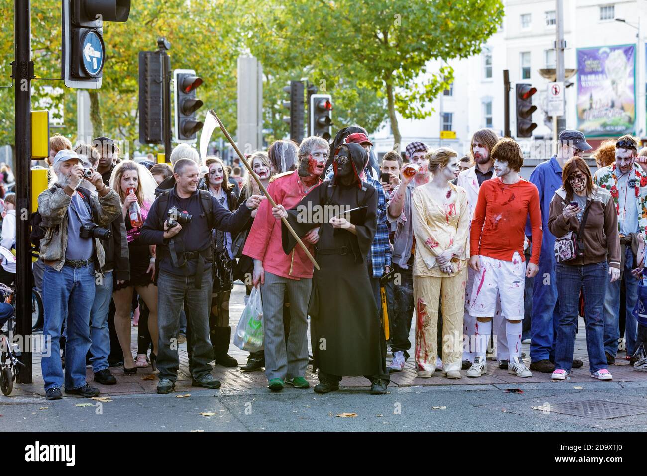 A group on people dressed up as zombies and onlookers wait to cross the road whilst following the route of the bristol Zombie walk in 2010 Stock Photo