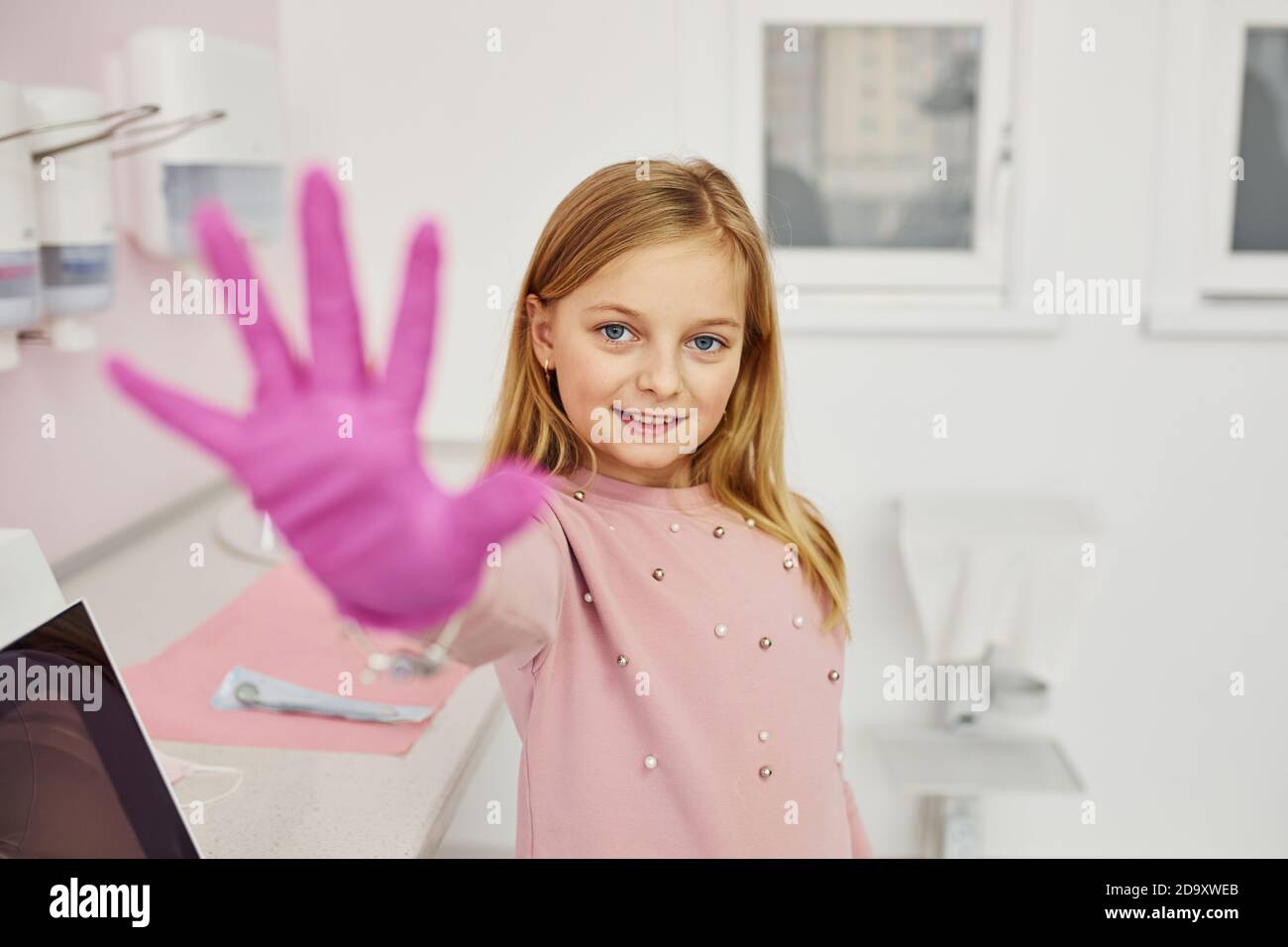 Little girl with gloves on hands standing in stomatology clinic Stock