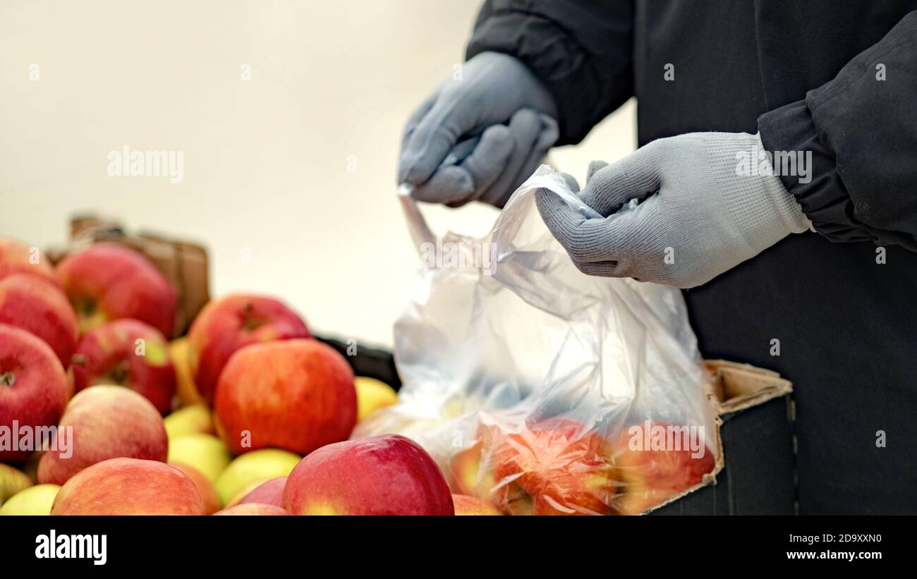 A young man wearing protective gloves buys food at a store during the coronavirus epidemic Stock Photo