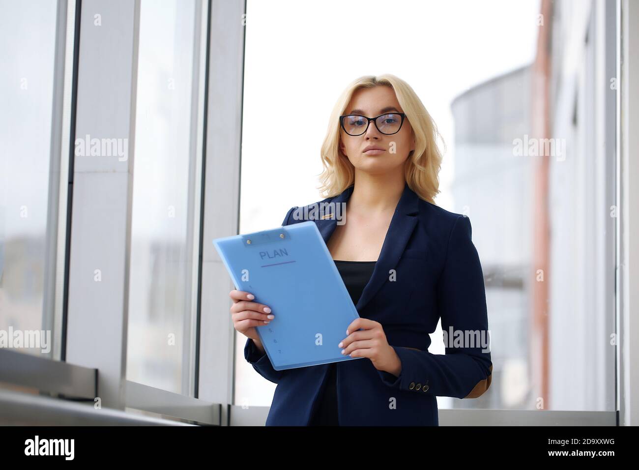 Photo of serious manager or director woman wearing formal clothing and eyeglasses holding in hands paper documents while working in office on laptop Stock Photo