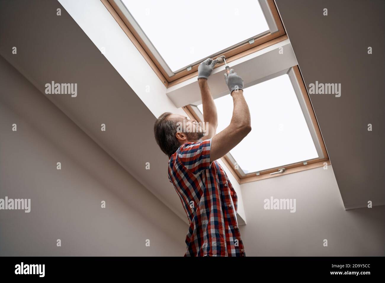 Young caucasian worker screwing skylight window handle Stock Photo
