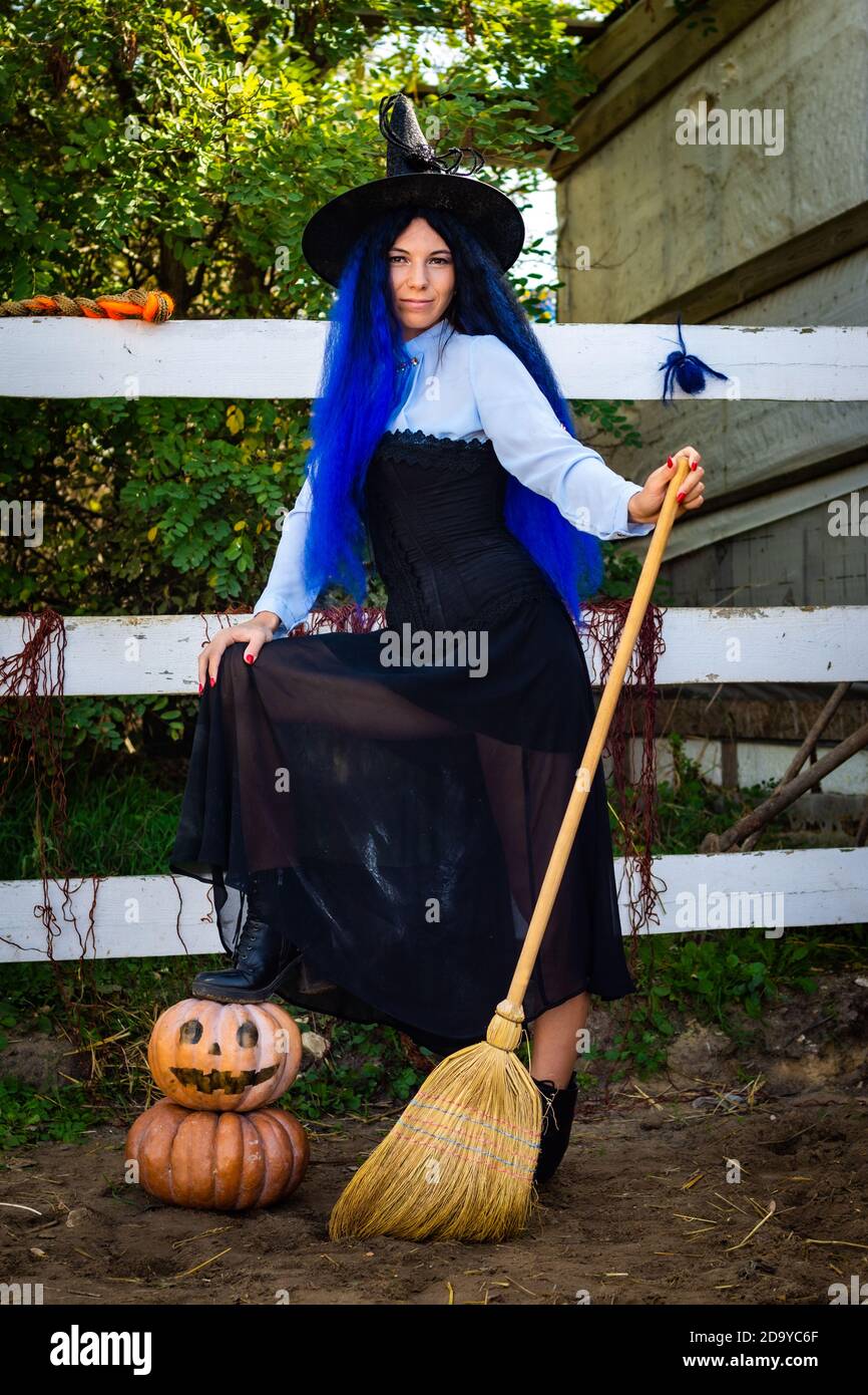 Cute girl in a witch costume with pumpkins and a broom Stock Photo - Alamy