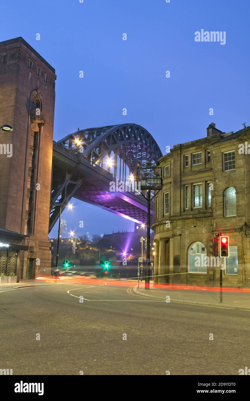 Light trails down on Newcastle's quayside looking towards the Tyne Bridge and Guildhall at dawn. Stock Photo