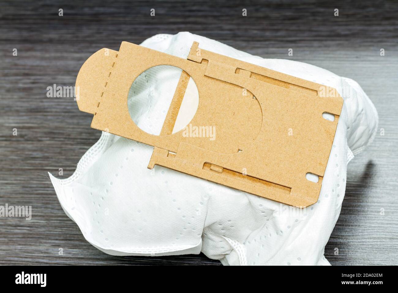 close-up of full synthetic vacuum cleaner bag on brown wooden background Stock Photo