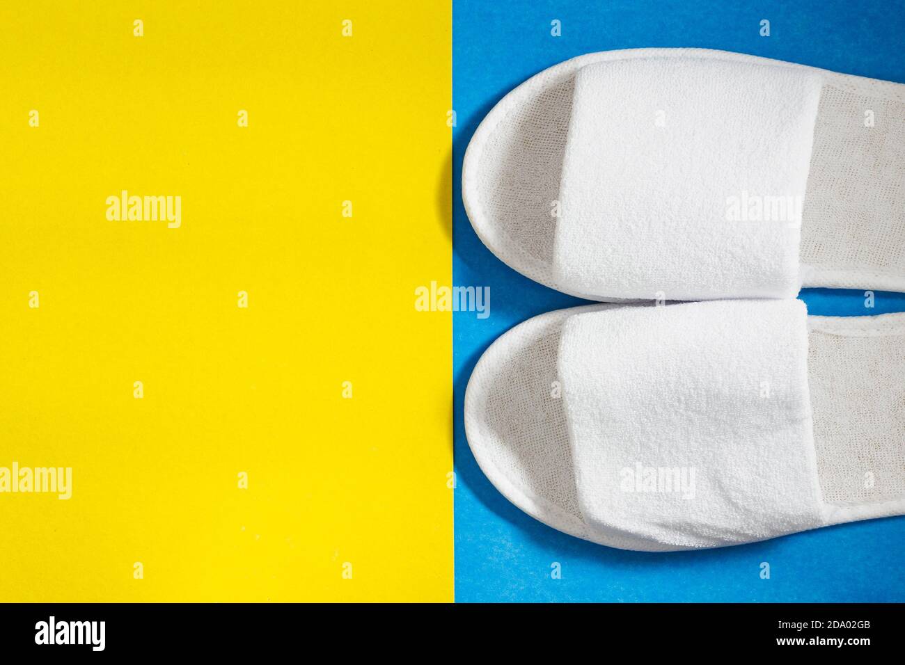 White slippers on a blue and yellow background. Top view, copy space for text Stock Photo