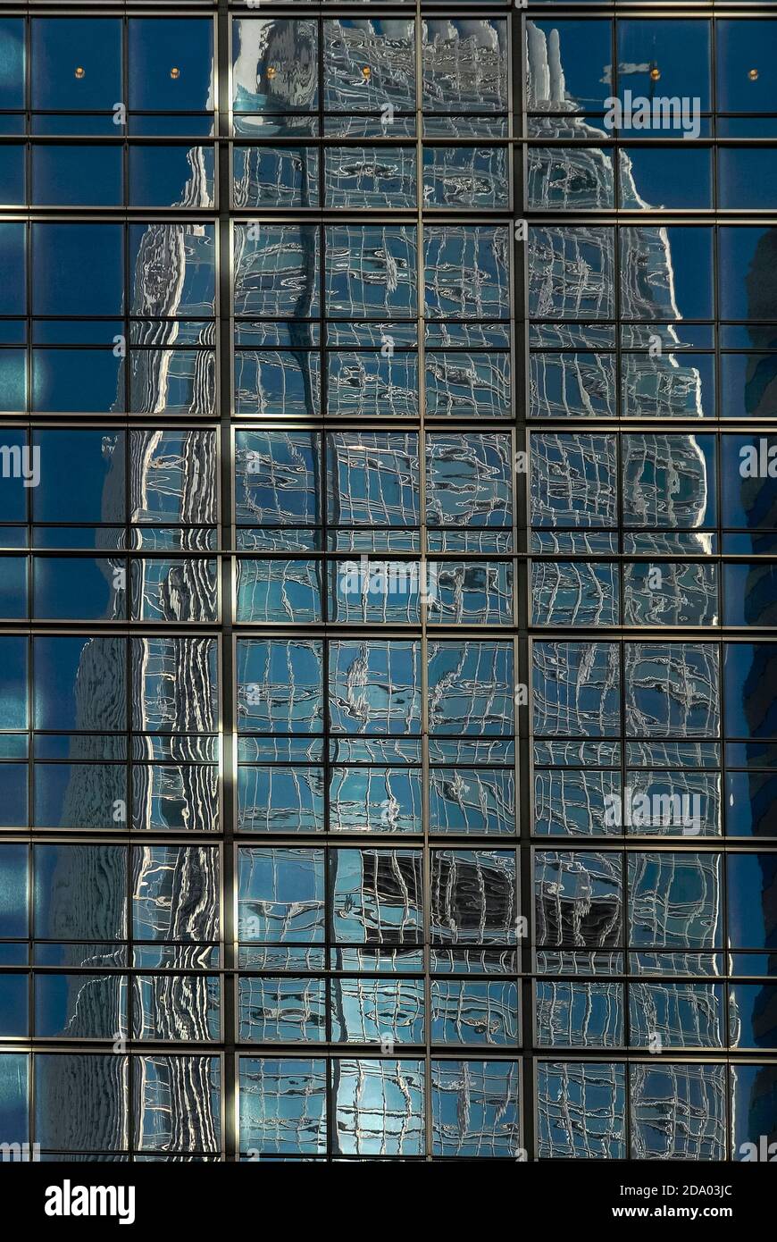 Reflective cladding on the side of the J.P. Morgan office tower in Chung Wan or Central District, Hong Kong, China, bends reality as it distorts and contorts the upper levels of one of the world’s tallest buildings, the 420m-high (1,378 ft) International Finance Centre Two (IFC2), into a mass of fragmented and tangled metal and glass. Stock Photo