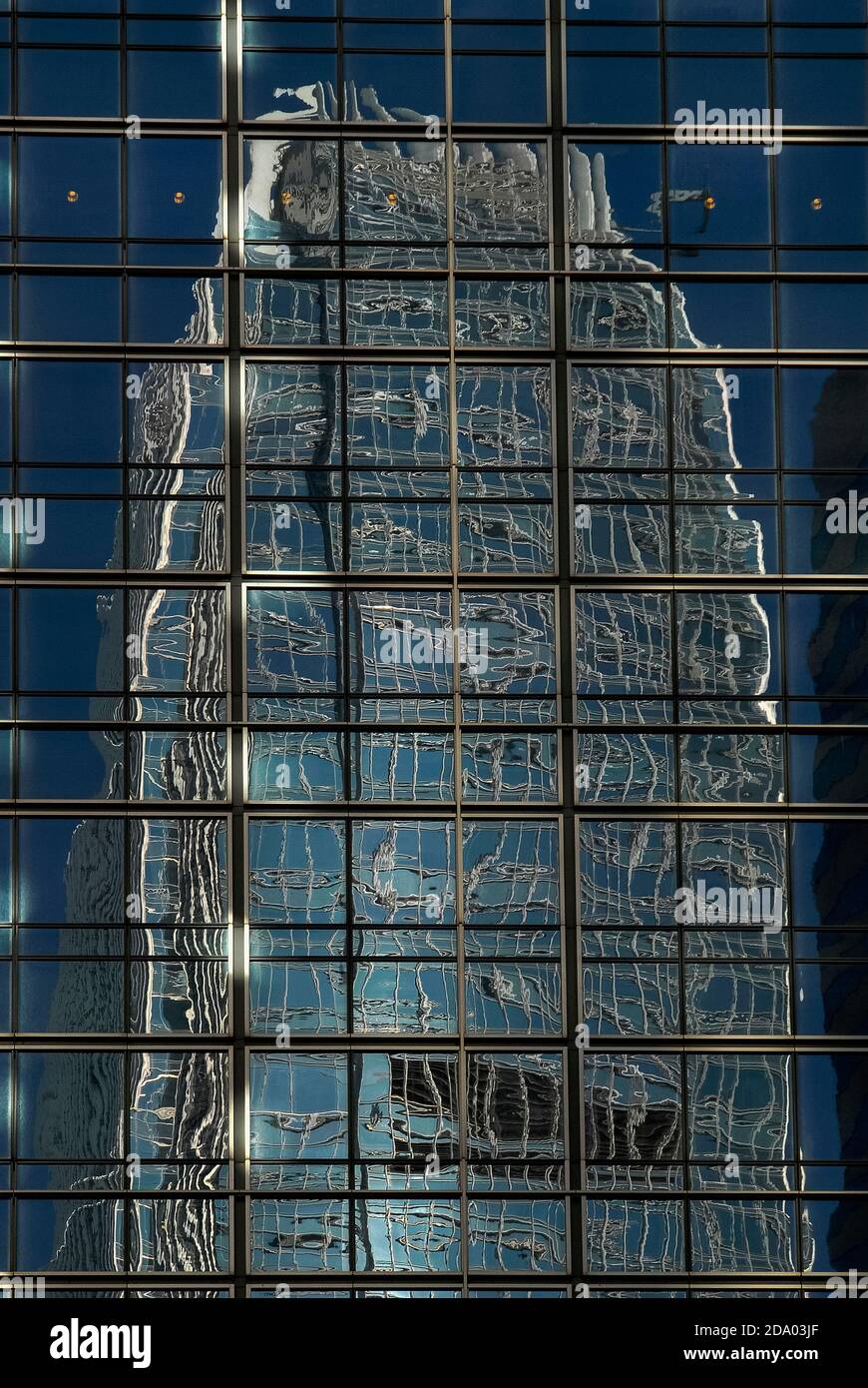 The upper floors of one of the world’s tallest buildings, the 420m-high (1,378 ft) International Finance Centre Two (IFC2), are contorted and distorted into a mass of tangled metal and glass when they are seen reflected in the cladding on the side of the J.P. Morgan office tower in Chung Wan or Central District in Hong Kong, China. Stock Photo