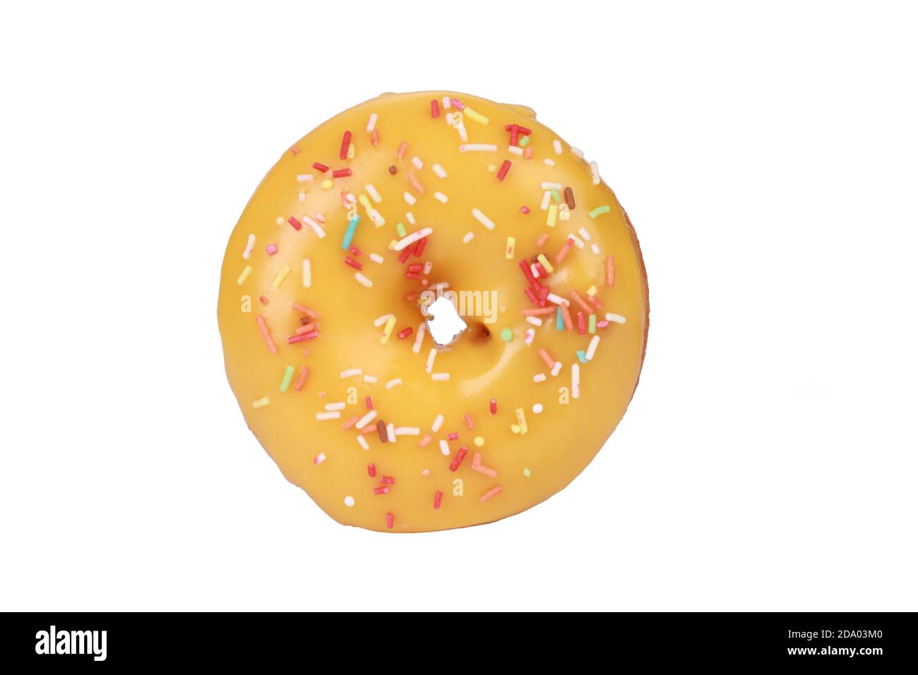Top view closeup of a donut with yellow icing and sprinkles on a white ...