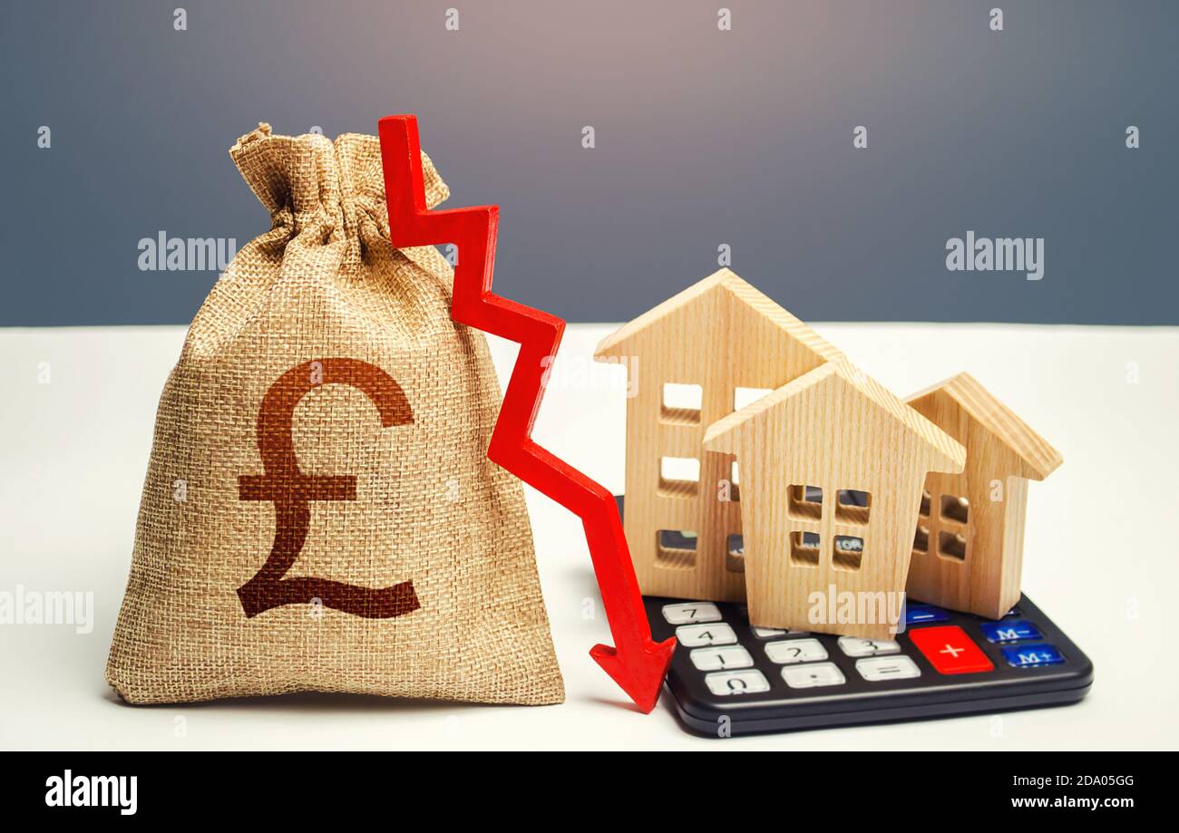 British pound sterling money bag with down arrow and houses on calculator. Falling real estate market, low prices and demand. Saving resources and red Stock Photo