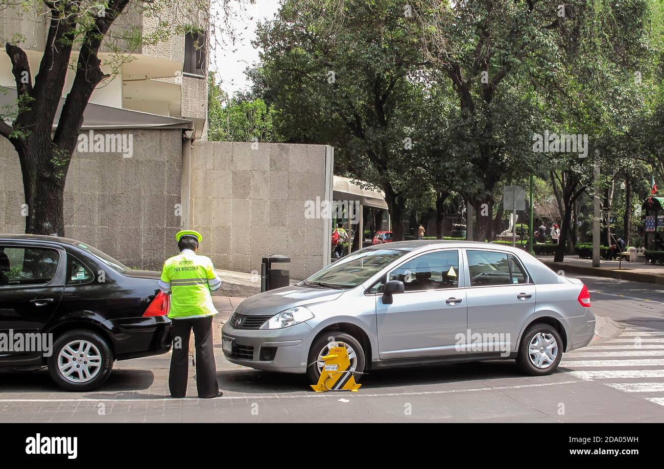 Traffic warden issuing fine ticket for car wheel clamped for parking on pedestrian crossing, Mexico City, Mexico Stock Photo