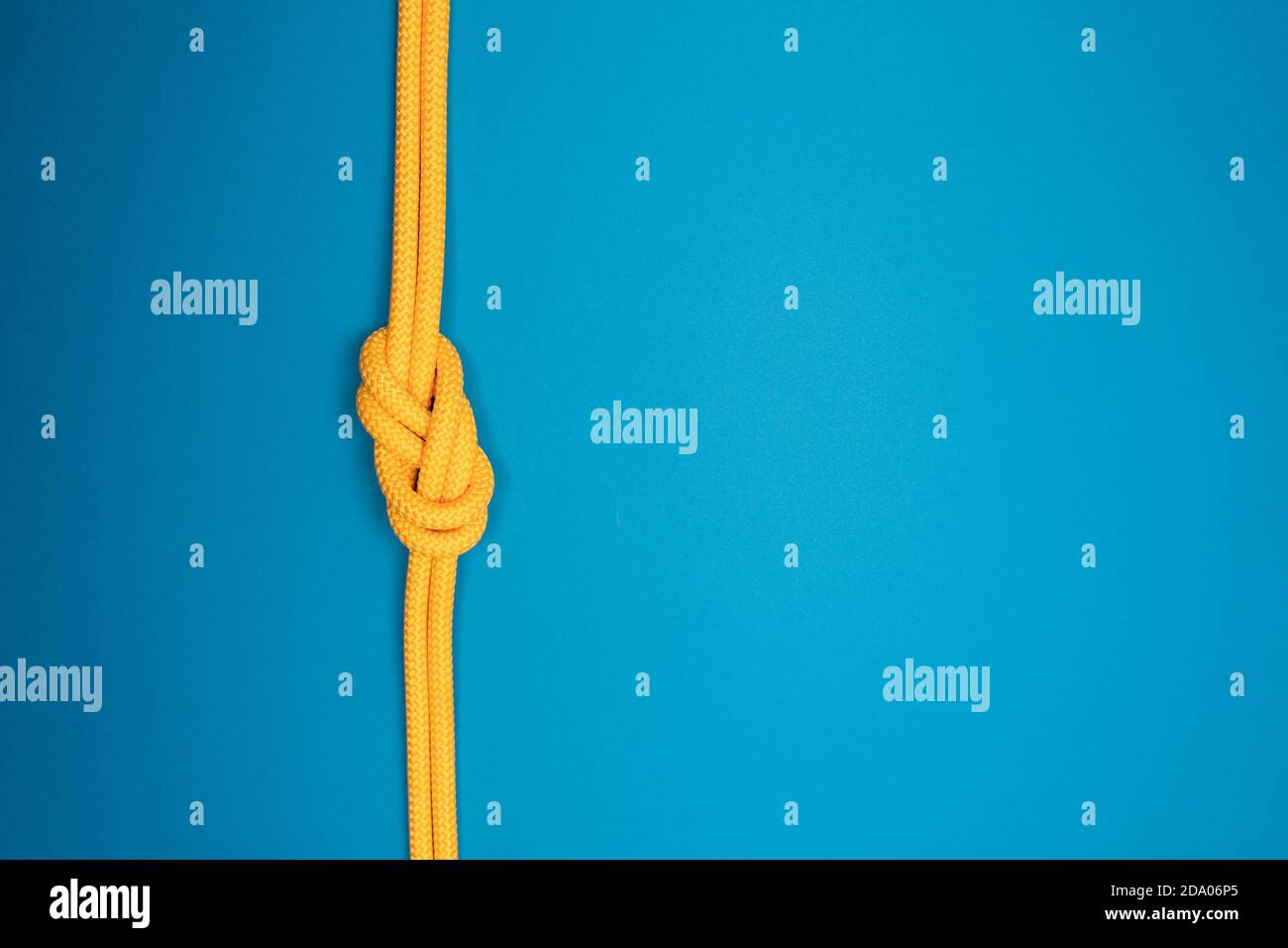Figure-eight knot with yellow climbing rope on blue background Stock Photo