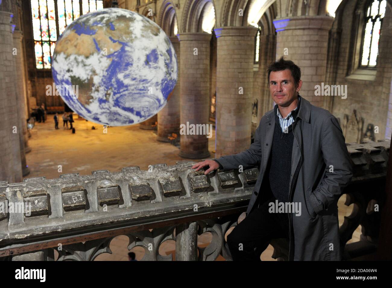 Artist Luke Jerram with his work.   He has the whole world in his hands or more specifically the whole earth in Gloucester Cathedral.    A touring art Stock Photo