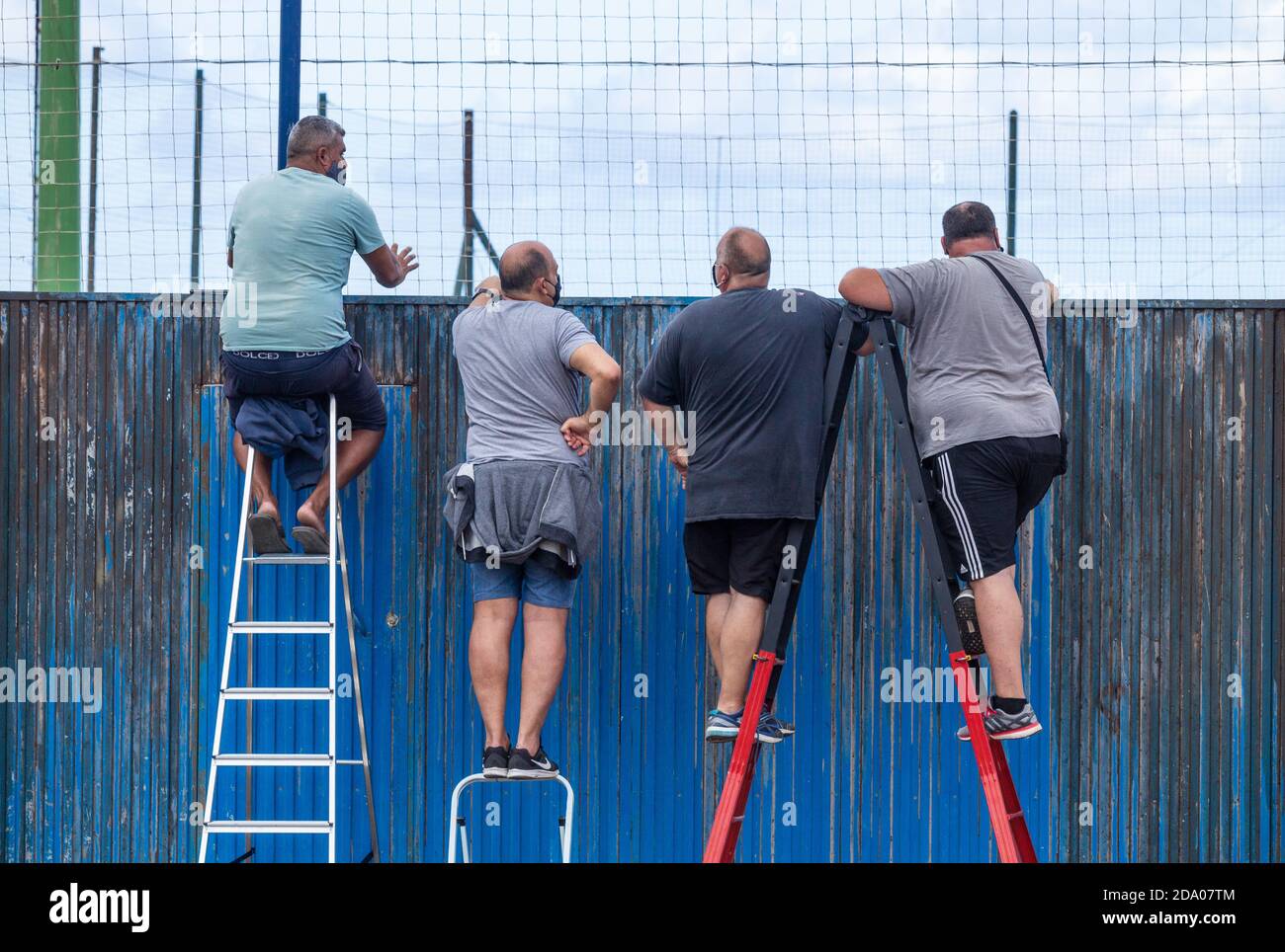Las Palmas, Gran Canaria, Canary Islands, Spain. 8th November, 2020. Football fans on Gran Canaria using ladders to watch local derby game. Covid restrictions means games have to played behind closed doors. Credit: Alan Dawson/Alamy Live News Stock Photo