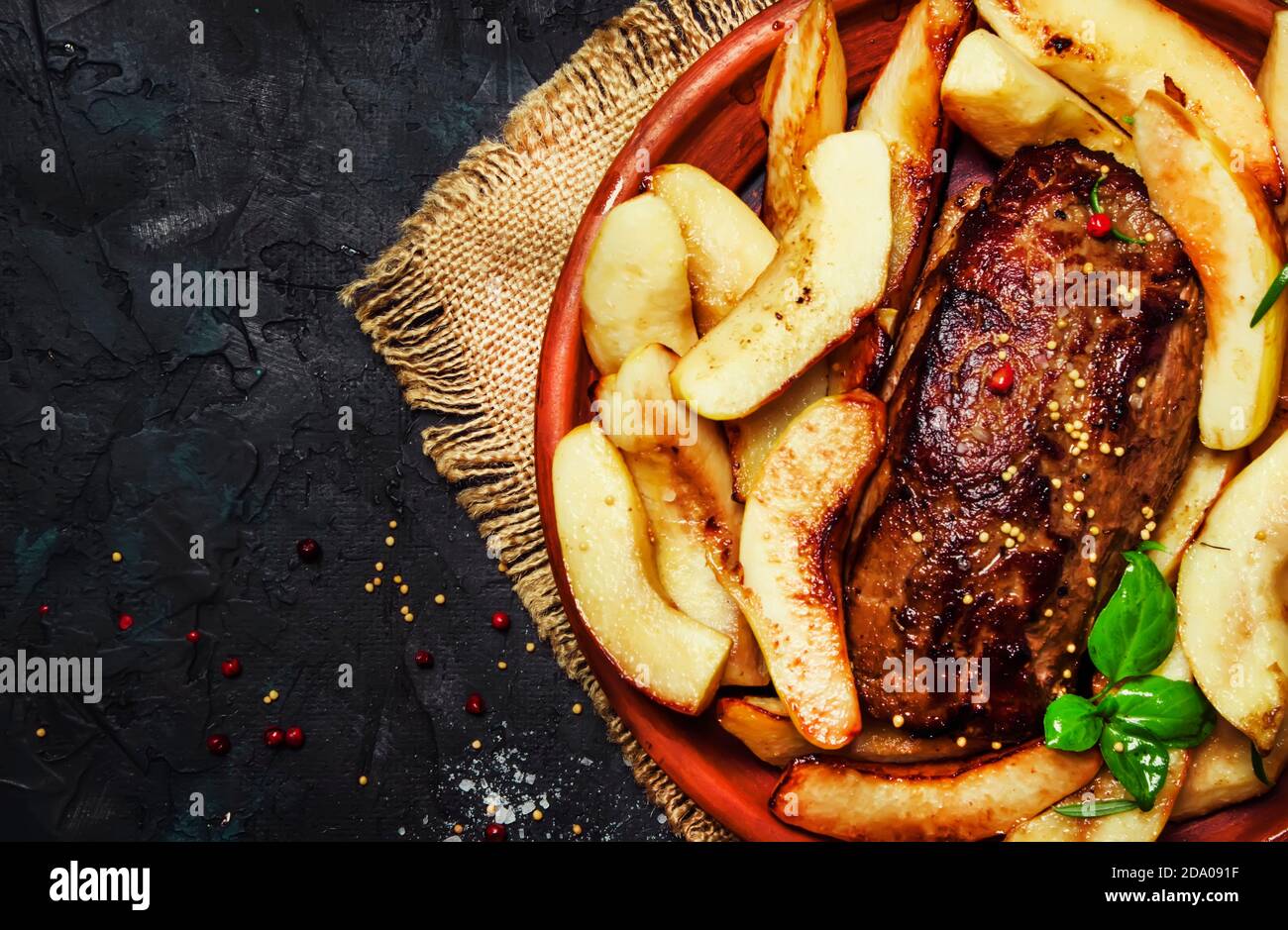 Fried pork tenderloin with quince, dark background, top view Stock