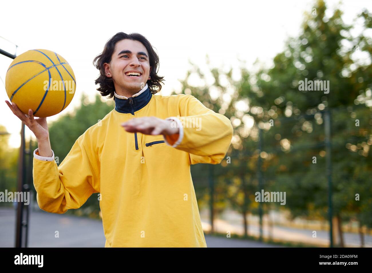 portrait of long haired caucasian teen boy with ball in ands, sportive boy keen on basketball Stock Photo