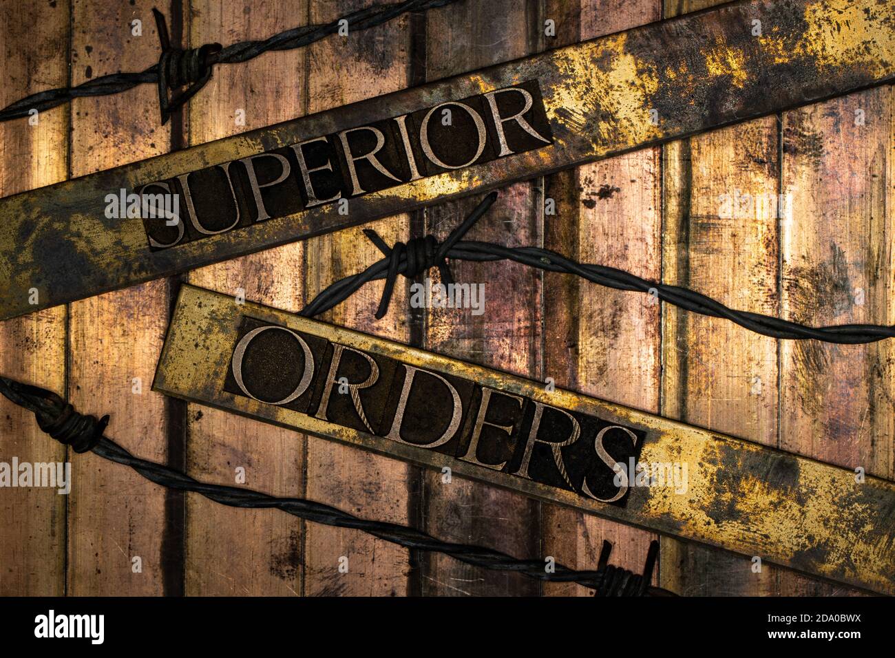 Superior Orders or Befehl ist Befehl text message on textured bronze grunge copper and vintage gold background with barbed wire Stock Photo